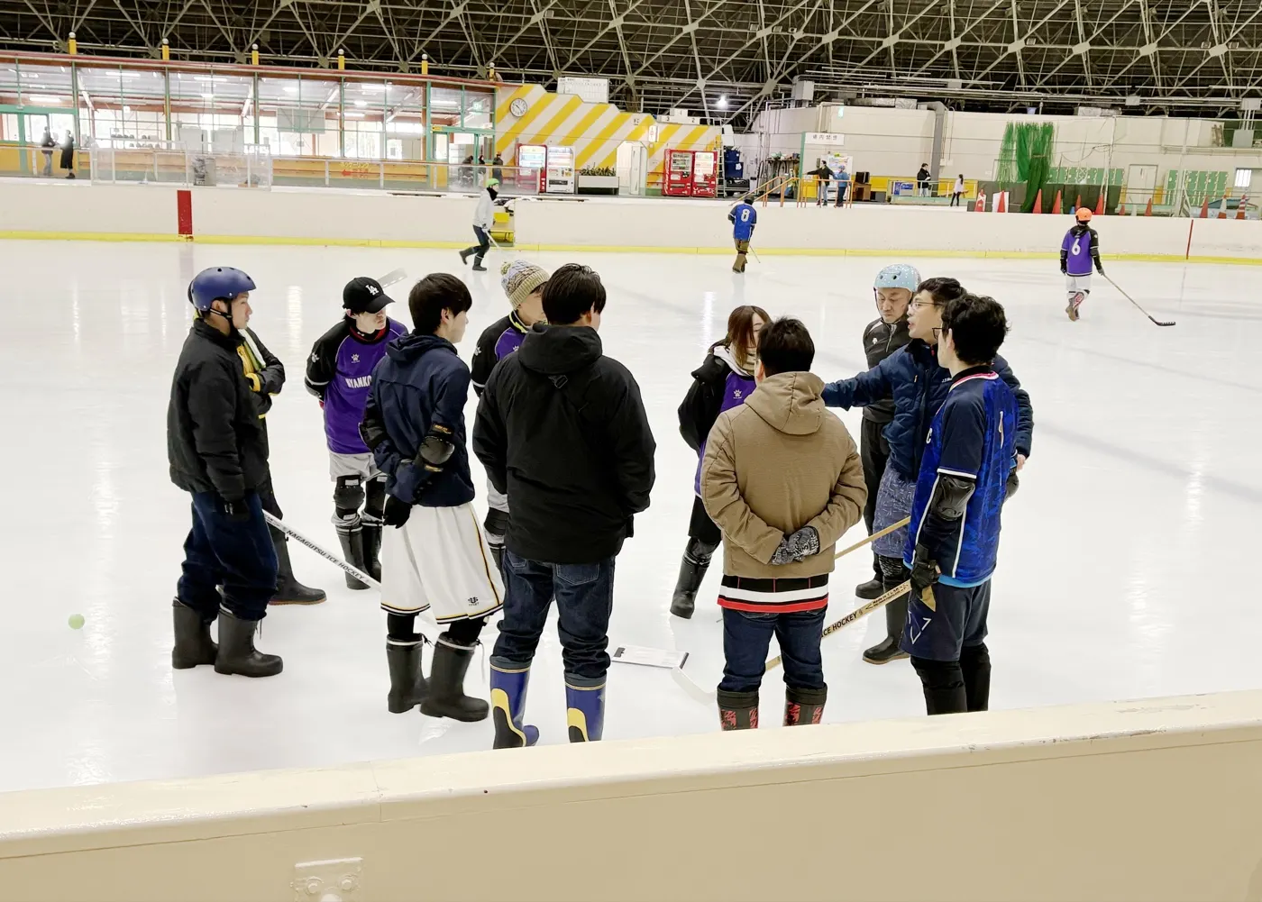 リンクの上で輪になって話し合う、連盟の役員と選手たち