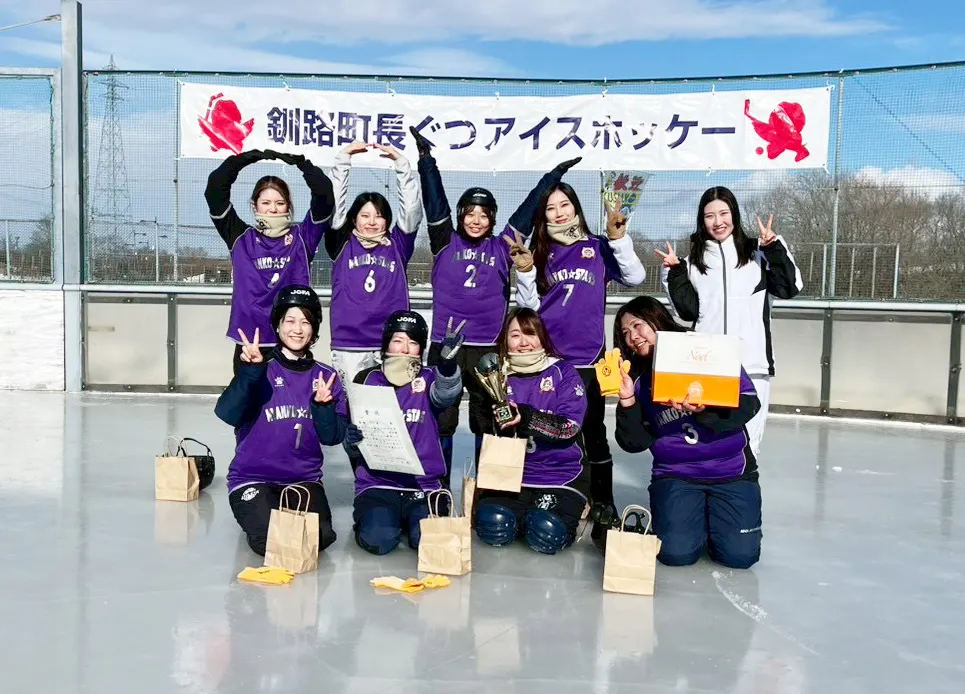 全国大会の女子の部で優勝し、横断幕の前で喜ぶ秋田の女子チーム